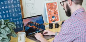 Person working on a laptop at a desk with creative design elements, illustrating digital marketing and web design concepts.