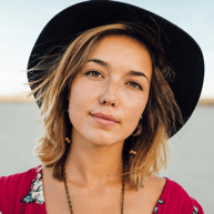 Smiling woman in a floral dress and black hat, embodying creativity and confidence, representing the team at Star Digital Strategies.